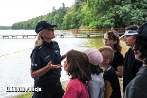 Policjantka rozmawia z dziećmi o bezpieczeństwie nad wodą.