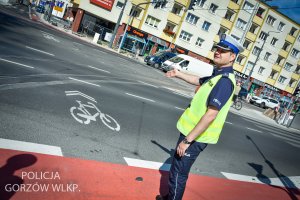 policjant wskazuje dłonią na drogę