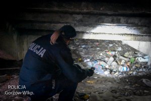 policjantka z latarką sprawdza teren pod schodami